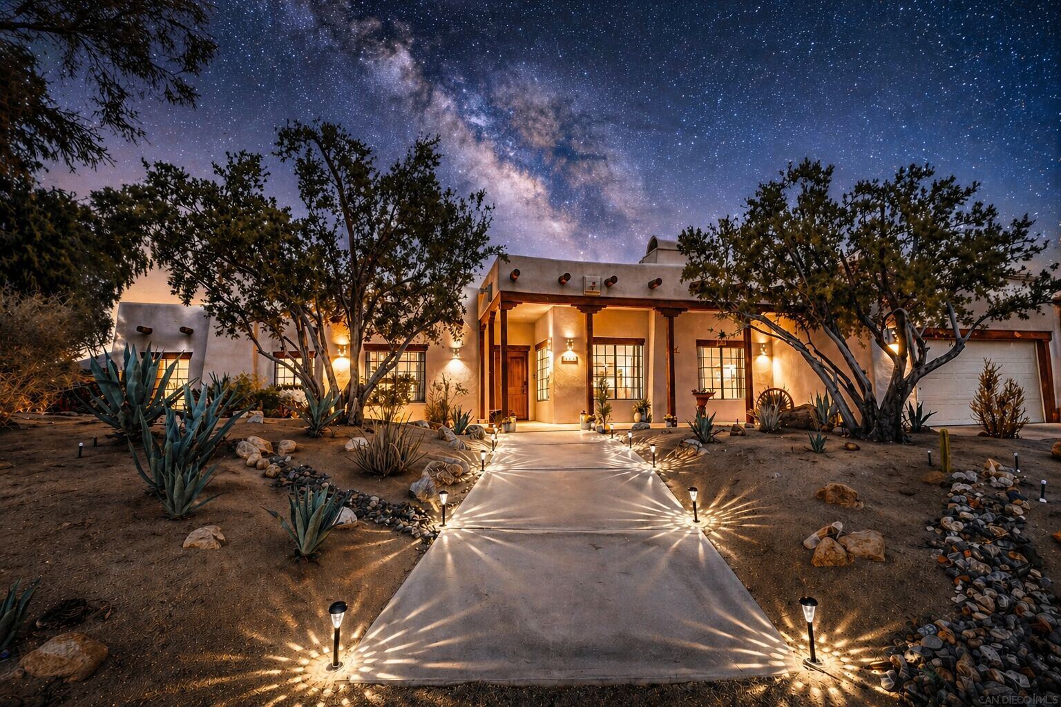 Moonlight Oasis at night — adobe pueblo residence with glowing path lights beneath the Milky Way in Borrego Springs